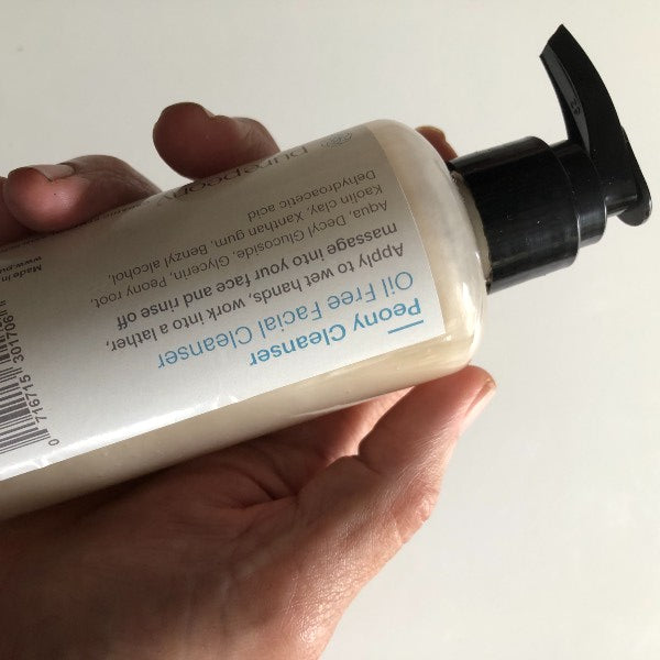 peony cleanser in glassheld in hand upside down