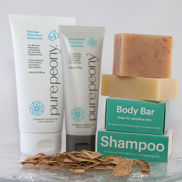 pure peony natural moisturiser for dry itchy skin in sugarcane tube with high factor eczema cream in sugarcane tube and eczema soap and shampoo piled ontop of boxes stacked beside