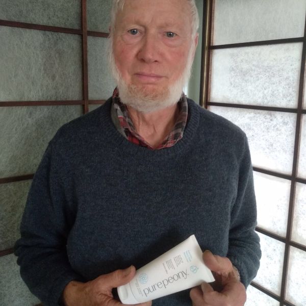 customer who is elderly man holding peony moisturiser for dry skin in front of body